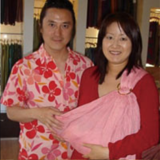 ピンクのスリングで赤ちゃんを抱くママと赤い花柄シャツの男性