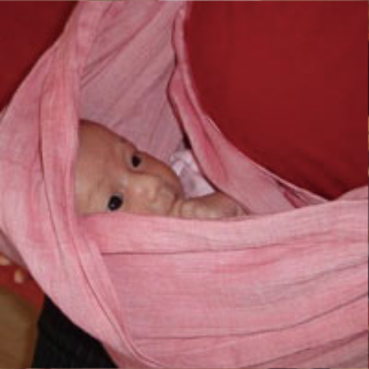 ピンクのスリングの中から顔をのぞかせる赤ちゃんのアップ