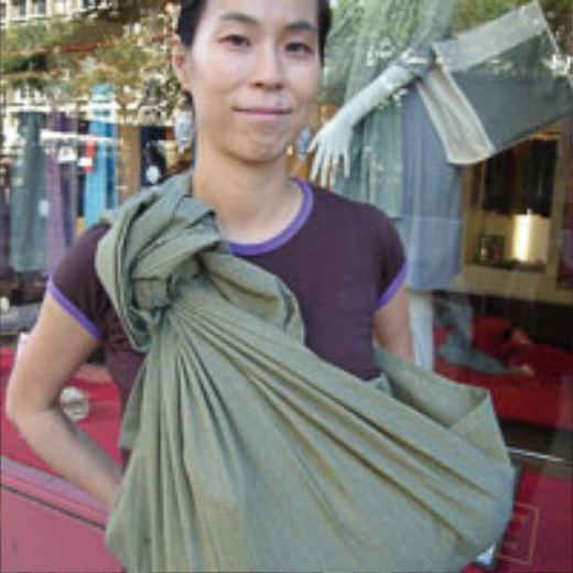 落ち着いたグリーンのスリングを着用した女性が店頭に立っている様子