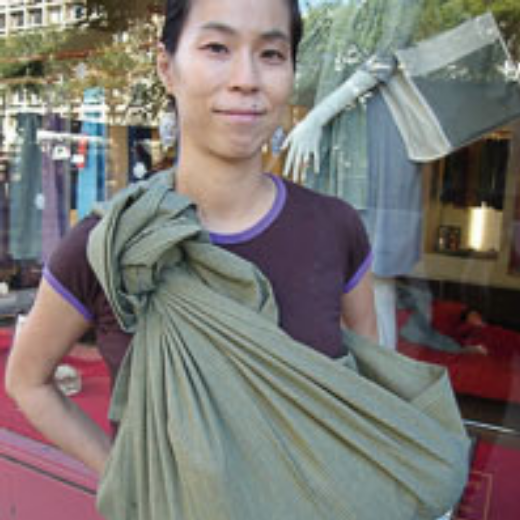 グリーンのスリングを身につけた女性が屋外でポーズ