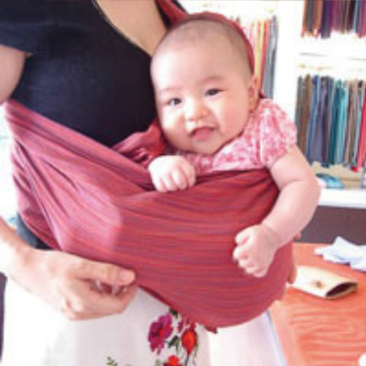 赤いグラデーションスリングで赤ちゃんを抱く女性