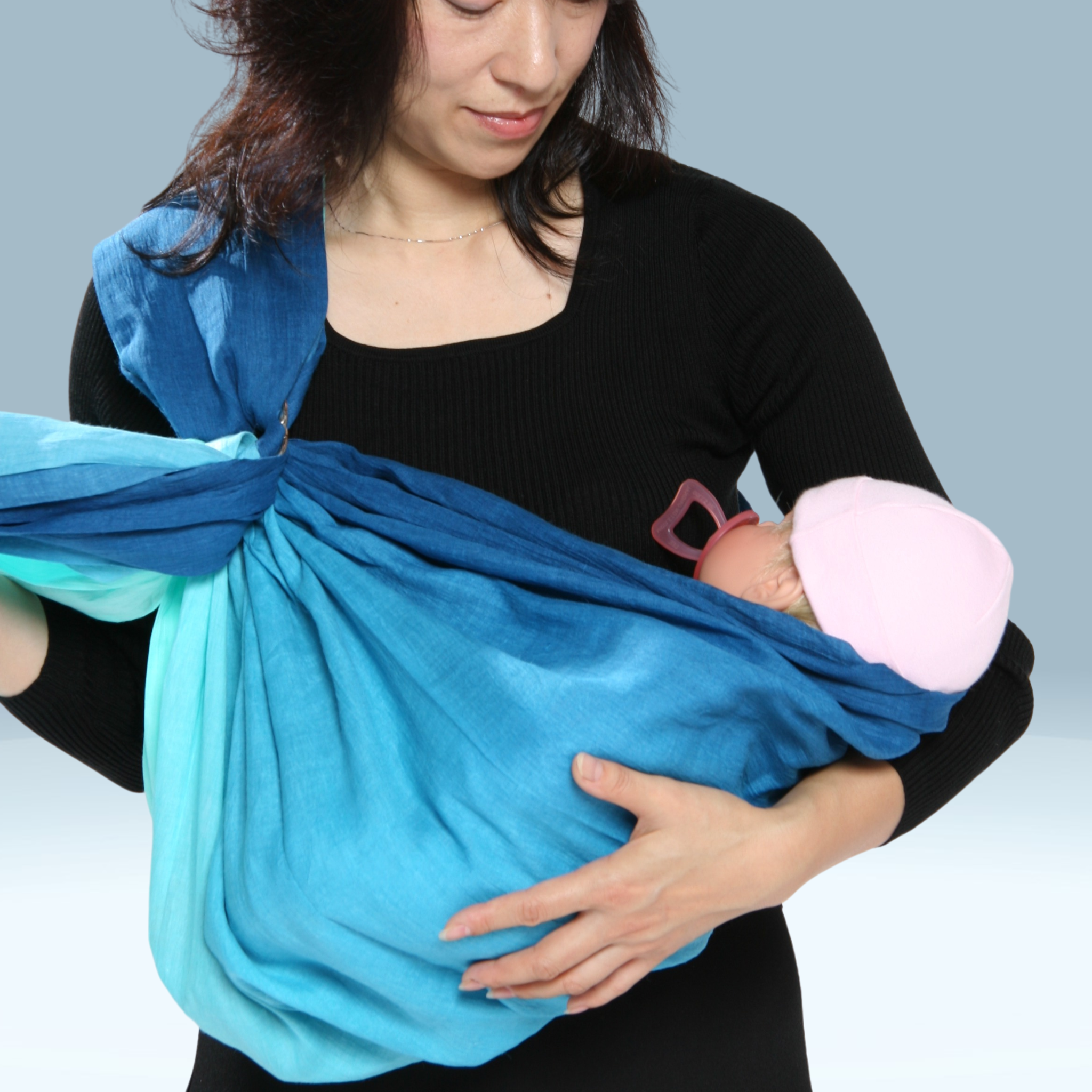 新生児をスリングでヨコ抱っこしている女性。赤ちゃんの頭がしっかりと見える位置で安定した姿勢