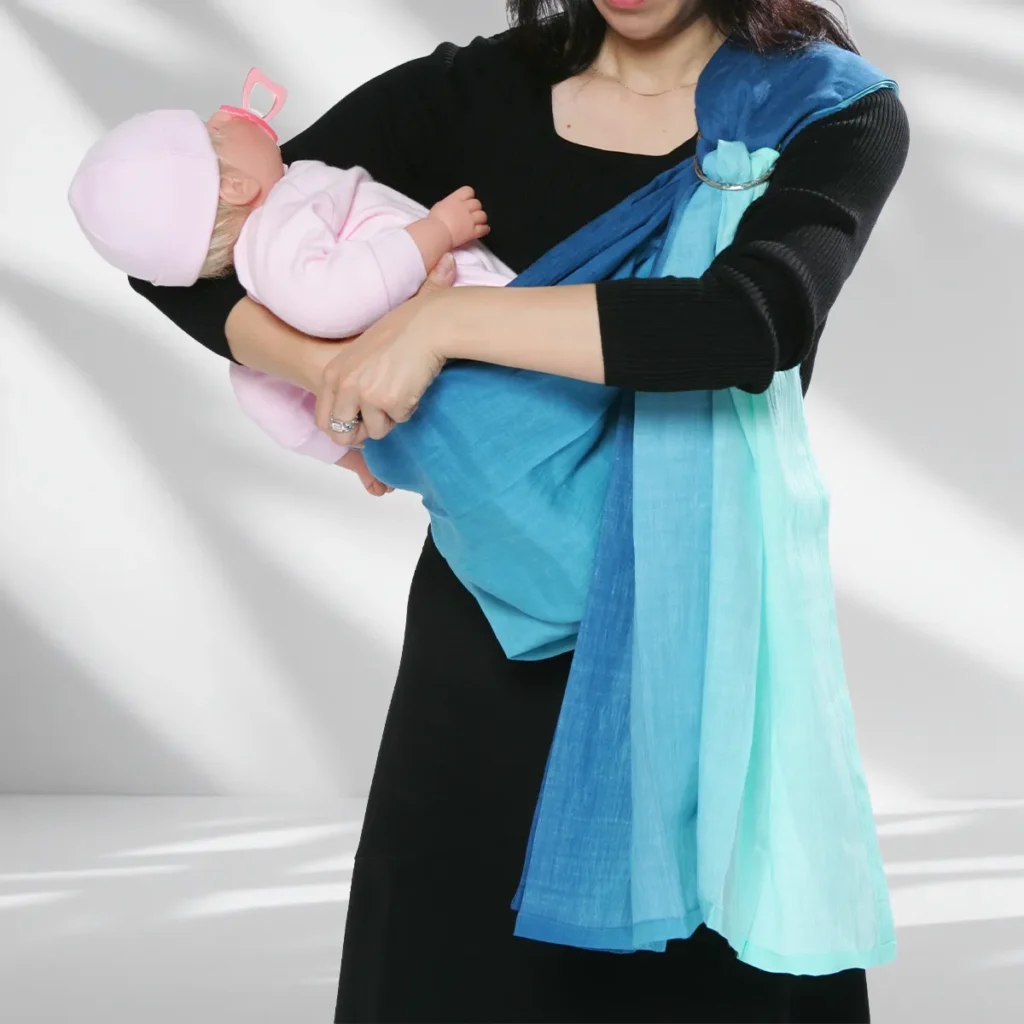 Hold the baby high on the opposite shoulder while opening the PsLing pouch to receive the legs